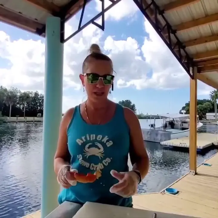Karri on the dock holding a large stone crab claw and a small hammer