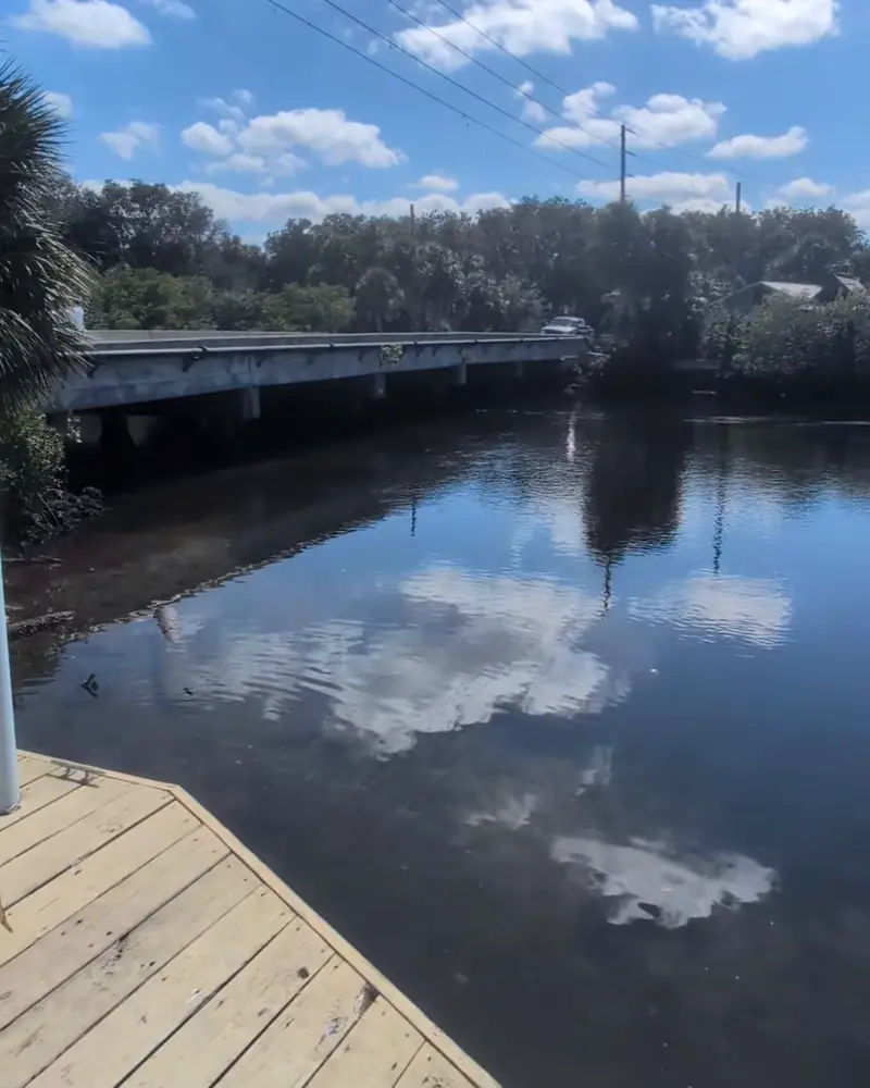 The creek behind the market, clouds in the water and the bridge beyond